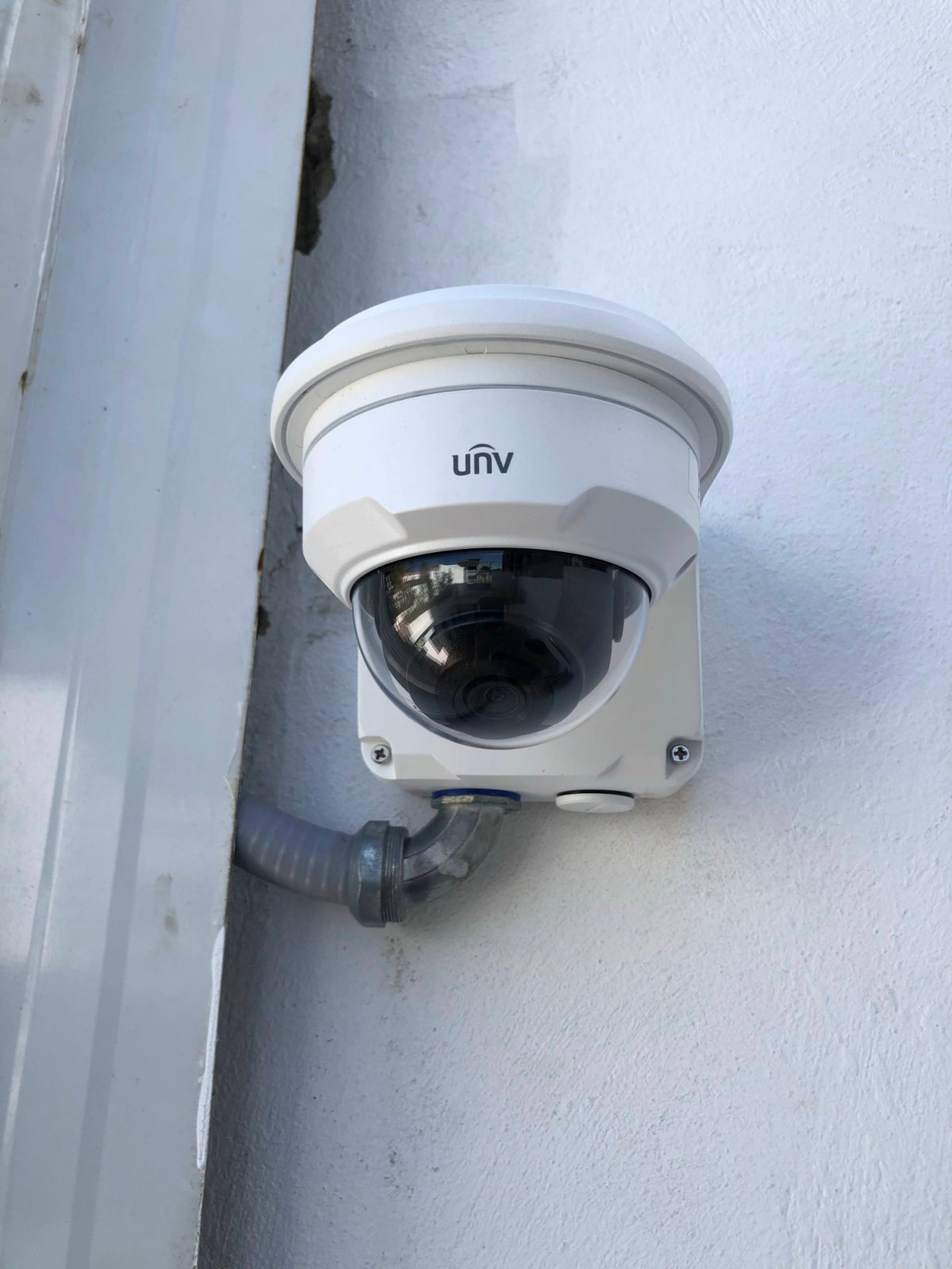 Cámara domo Uniview instalada en pared exterior con tubería metálica protegiendo el cableado