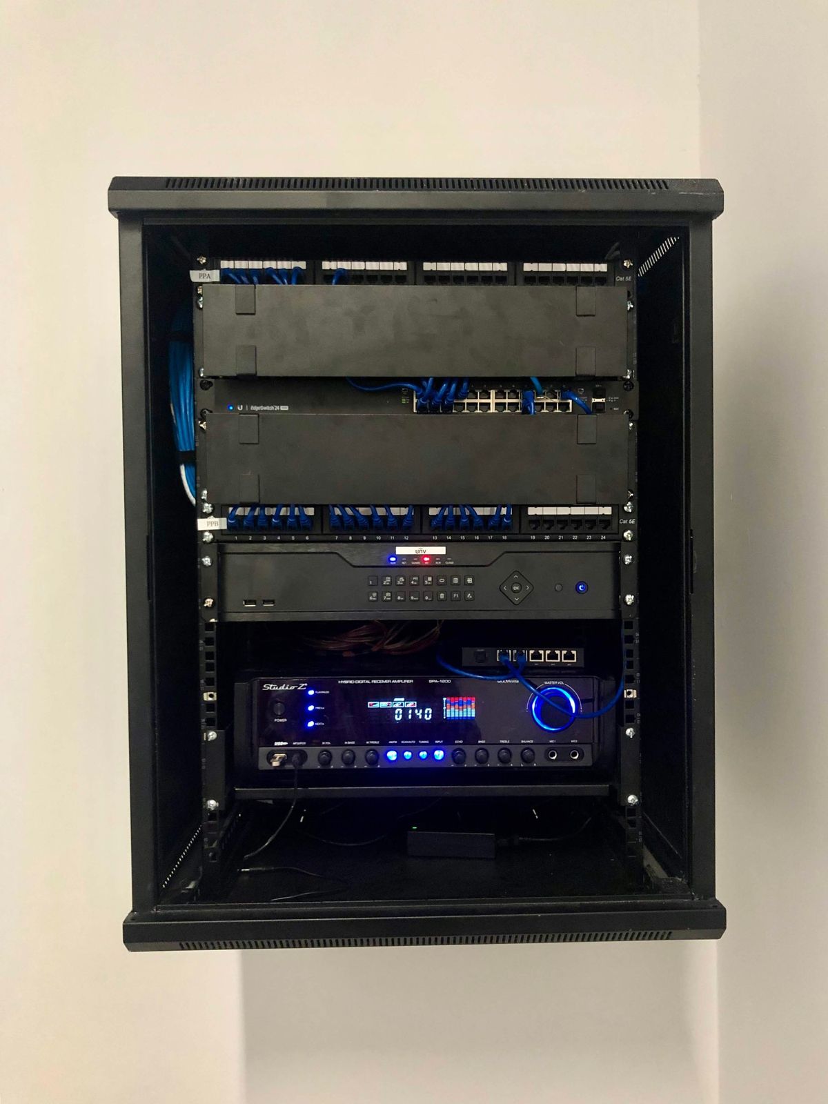 Gabinete de comunicaciones de pared con patch panels, switch, grabador de video Uniview y amplificador de audio